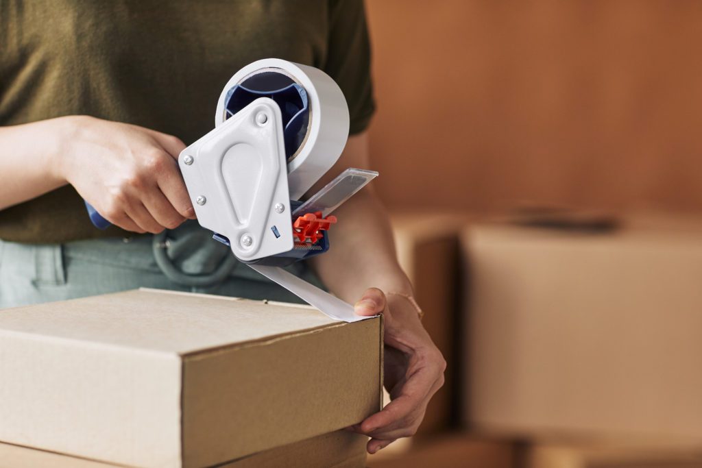Get creative with packing supplies - Close-up of woman packing moving boxes